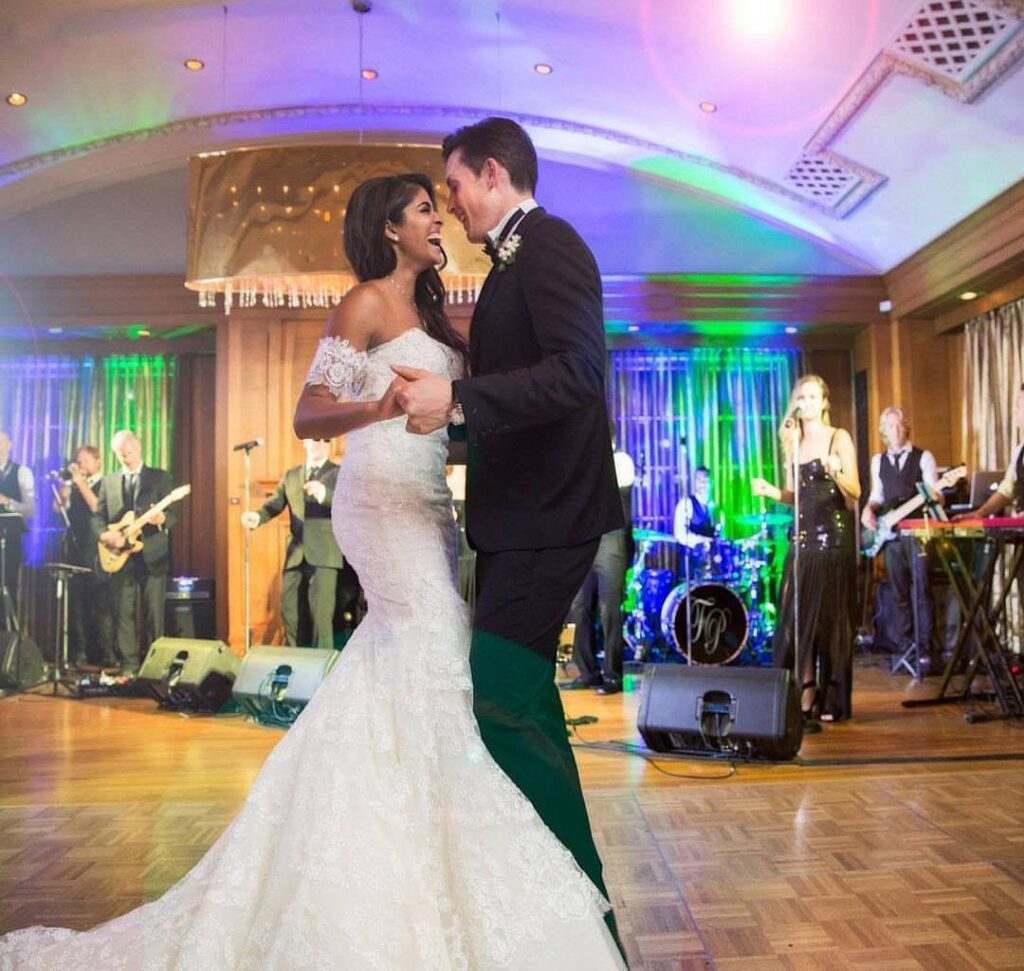Bride and groom sharing their first dance while Famous Players Band performs behind them